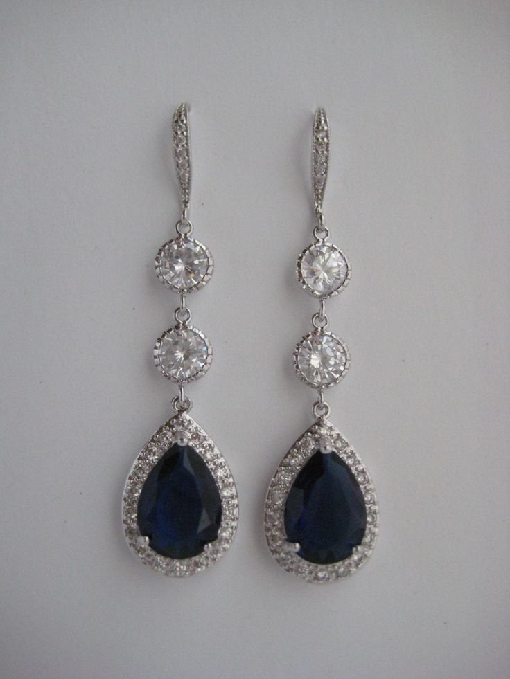 Luxury blue sapphire cubic zirconia bridal tear drop earrings in rhodium plated brass setting. Earrings feature a large teardrop with pear cut blue sapphire cubic zirconia center surrounded by tiny round zirconia crystals. Teardrop dangles from zirconia detailed ear wire and two round cubic zirconia connectors. Total length of the earring is 6 cms. For matching necklace click: https://www.etsy.com/listing/252994446/long-blue-sapphire-cubic-zirconia-bridal?ref=shop_home_active_22 For matching bra Blue Sterling Silver Chandelier Earrings For Wedding, Elegant Sapphire Earrings For Wedding, Sapphire Drop Earrings For Wedding, Silver Sapphire Earrings For Wedding, Formal Teardrop Sapphire Earrings, Teardrop Sapphire Wedding Jewelry, Sapphire Teardrop Earrings For Wedding, Sapphire Teardrop Pendant For Wedding, Blue Cubic Zirconia Teardrop Earrings For Wedding