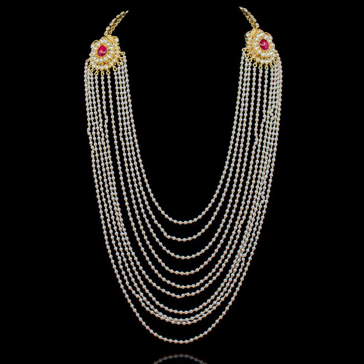 A stunning design, imbued with vintage glamour! Traditional mala with two kundan motifs on the sides and encrusted with kundan stones. Long dangling beaded chains are attached to the motifs. It works great for the grooms to pair with their sherwaanis. Approximate mala length is 13". Gold-plated on high-quality brass as base metal. Rahul Mala (Ruby) is in-stock & ready-to-ship. Delivery time frame for the Rahul Mala (Emerald) is 4-6 weeks. For custom or urgent requests, please contact support@ala Bridal Necklace With Stone Work For Diwali Rituals, Wedding Silver Beaded Temple Necklace, Gold Kundan Necklace In Traditional Drape, Temple Jewelry Tikka With Stone Work For Reception, Bollywood Bridal Necklace For Rituals With Latkans, Bollywood Style Beaded Jewelry For Rituals, Temple Style Bridal Necklace With Stone Work For Rituals, Festive Jeweled Kundan Necklace For Reception, Temple Style Bridal Necklace With Stone Work