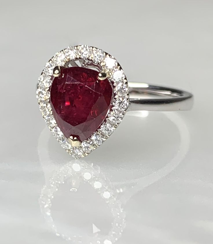 Ruby Engagement Ring, Ruby Engagement Ring White Gold, Pear Shaped Ruby Ring, Pear Shaped Ruby Engagement Ring, 2 Carat Ruby Ring, Ruby Ring A classic and mesmerizing genuine ruby ring featuring a lustrous pear shaped center stone weighing 2.22 carats surrounded by a traditional halo of sparkling white diamonds weighing 0.66 carats. *Approximate ring weight: 3.33 grams *Ring size: 7 * Complimentary resizing is available up to 3 sizes larger or smaller than stated size. Gia Certified Teardrop Ring For Anniversary, Gia Certified Pear-shaped Ring For Anniversary, Gia Certified Pear-shaped Diamond Promise Ring, Silver Pear-shaped Ring With Halo Setting, Gia Certified Pear Diamond Ring, Gia Certified Pear-shaped Anniversary Rings, Pear-shaped Gia Certified Rings For Anniversary, Gia Certified Teardrop Wedding Rings, Gia Certified Teardrop Diamond Ring