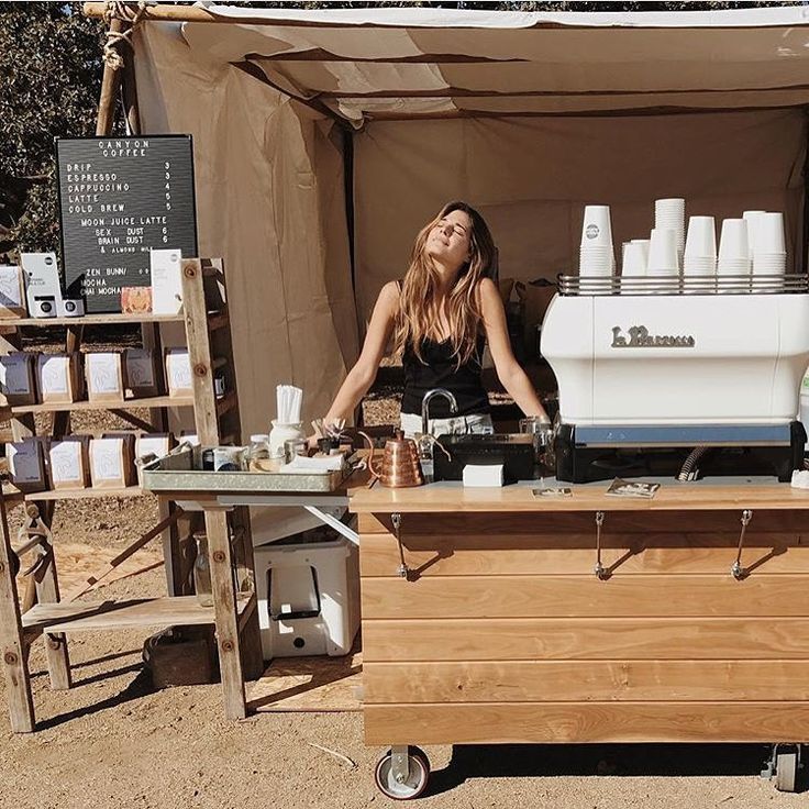 a woman standing behind a counter in front of a tent