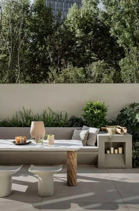 an outdoor seating area with tables and chairs in the foreground, surrounded by greenery