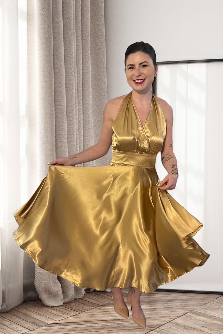 Introducing the ultimate embodiment of 1970s disco glamour: our dazzling Gold Halter Dress! This enchanting gown is a shimmering tribute to the era of disco balls, dance floors, and electric energy. With its captivating design and luxurious details, it's the perfect choice for those seeking to channel their inner disco diva.Crafted from a lustrous gold fabric that catches the light with every step, this dress radiates opulence and extravagance. The halter neckline, reminiscent of the iconic '70s Glamorous Satin Dress For Prom, Gold Satin Cocktail Dress, Glamorous Satin Dress For Party And Prom Season, Glamorous Satin Dress For Prom Party, Glamorous Satin Cocktail Dress For Party Season, Glamorous Satin Midi Dress For Party, Glamorous Satin Evening Dress For Party Season, Glamorous Evening Satin Dress For Party Season, Fitted Gold Satin Dress For Night Out