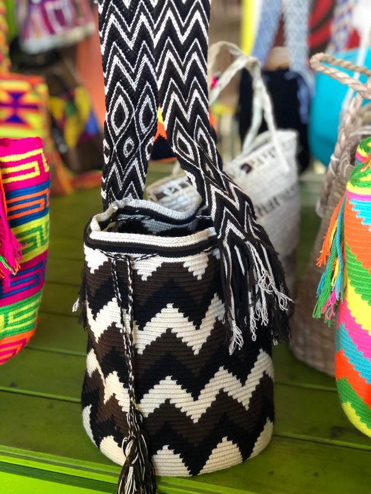 colorful baskets are lined up on a shelf in a store, some with tassels hanging from them