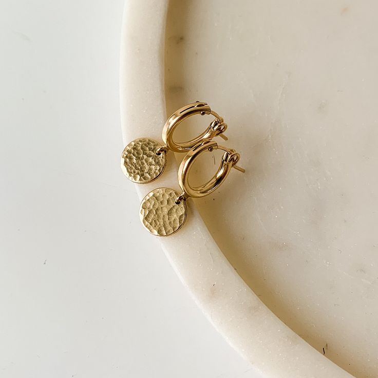 ✤ 14k gold filled ✤ hoops: 13mm ✤ coin charms: 8mm DETAILS: Our most loved earring, these gold huggie hoops are sure to become your go-to earring!  The small tube style hoops have textured charms that radiate the light. All components are 14k gold filled so you can wear these daily!  ✤Also available in 925 sterling silver.  SHIPPING: ✤I offer FREE shipping within Canada but please note that this does NOT include tracking.  If you choose FREE shipping, you risk your package getting lost in transi Hammered Gold Earrings, Dainty Yellow Gold Huggie Earrings With Dangling Charms, Yellow Gold Huggie Earrings With Dangling Charms For Everyday, Elegant Gold Huggie Earrings With Dangling Charms, Everyday Yellow Gold Huggie Earrings With Dangling Charms, Handmade Gold Huggie Earrings In Brass, Handmade Gold Brass Huggie Earrings, Yellow Gold Brass Huggie Earrings Gift, Gold-plated Dangle Huggie Earrings