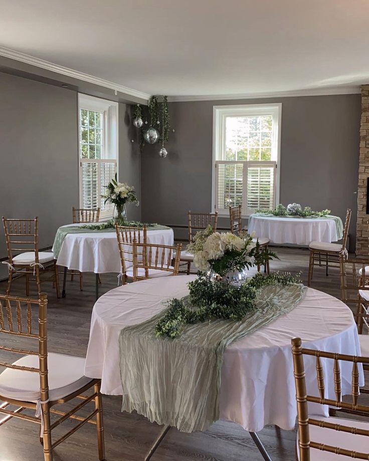 a room filled with tables and chairs covered in white tablecloths