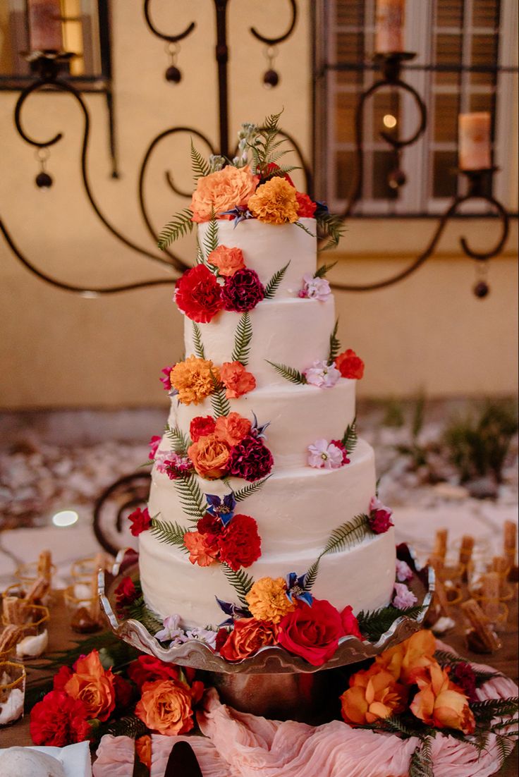 a multi - tiered wedding cake with orange and red flowers