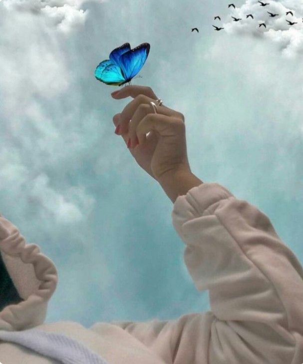 a woman holding a blue butterfly in the air with birds flying above her and behind her