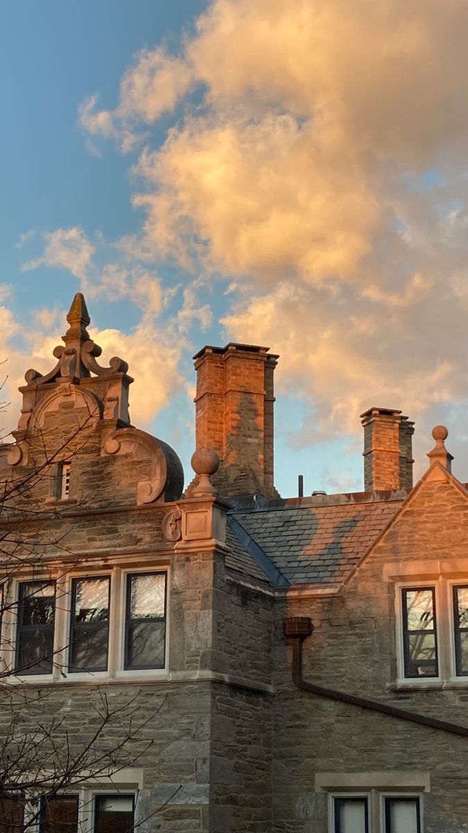 an old brick building with two chimneys on the top and one at the bottom under a cloudy sky