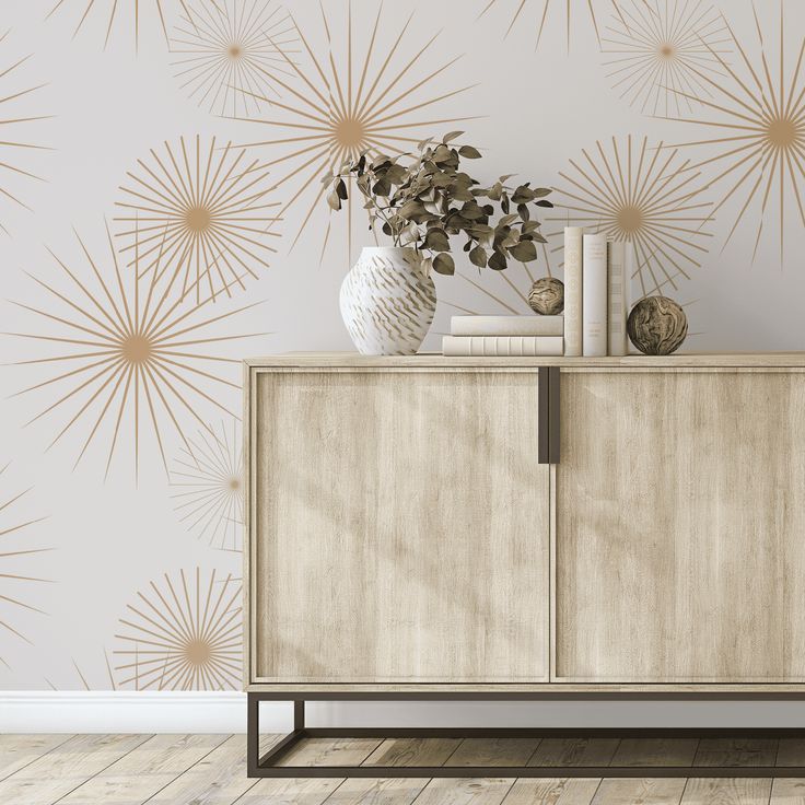 a white vase sitting on top of a wooden cabinet next to a wall with gold stars