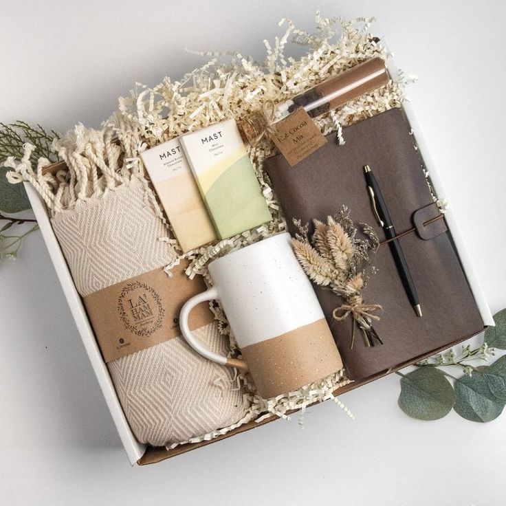 an open box containing coffee, notebooks and other items with greenery on the side