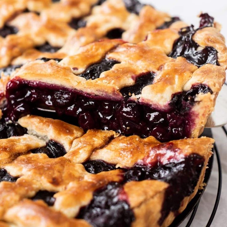 blueberry pie with latticed crust sitting on a wire rack next to another pie