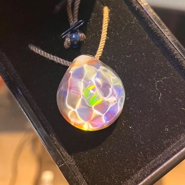 Discover the enchanting beauty of our Opal Gemstone Ocean Reflection Pendant. This meticulously handcrafted borosilicate glass artwork, inspired by the mesmerizing hues of the sea, captures the essence of ocean waves in a stunning gradient of blues and greens. Each pendant, a unique Tears of the Sea creation, shimmers in sunlight, reminiscent of the captivating play of light on water surfaces. Ideal for swimmers, surfers, and sea lovers, this necklace offers more than just an accessory - it's a Multicolor Glass Crystal Necklace Gift, Multicolor Glass Crystal Necklace For Gift, Multicolor Glass Crystal Necklaces For Gifts, Elegant Iridescent Glass Necklaces, Unique Iridescent Glass Necklaces, Clear Glass Round Pendant Jewelry, Clear Glass Healing Jewelry, Clear Glass Jewelry For Healing, Multicolor Recycled Glass Necklace As Gift