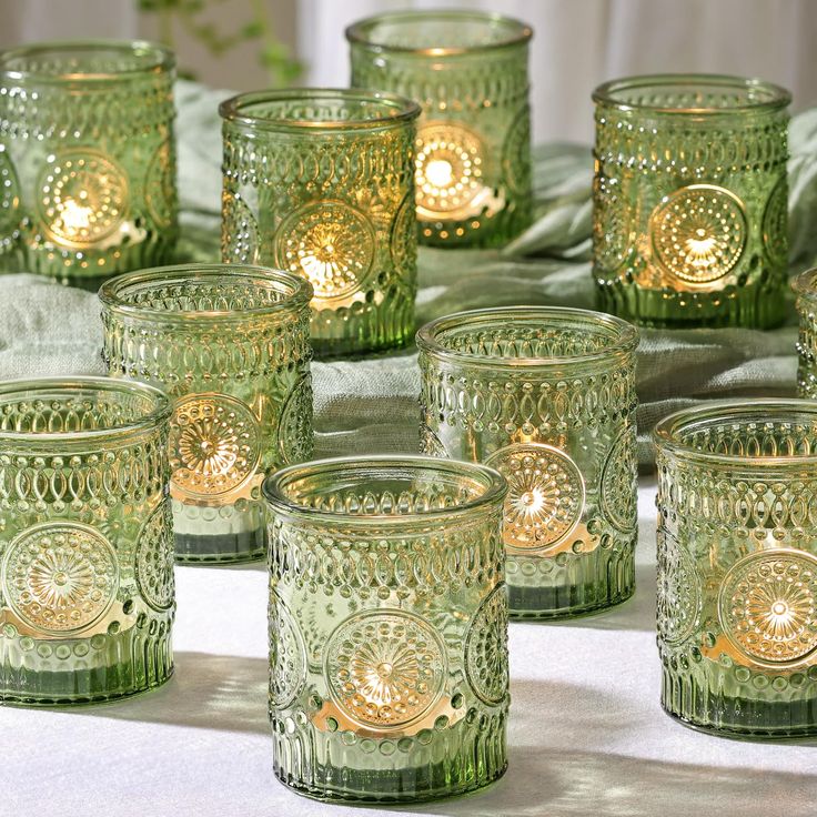 many green glass candles are lined up on the table