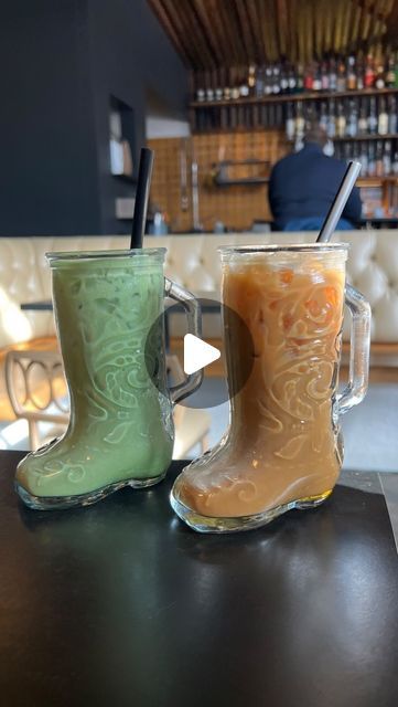 two glass boots sitting on top of a table next to a cup filled with liquid