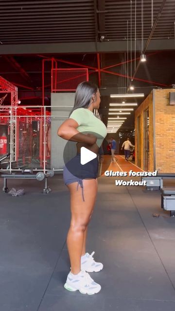 a woman standing in the middle of a gym with her back turned to the camera