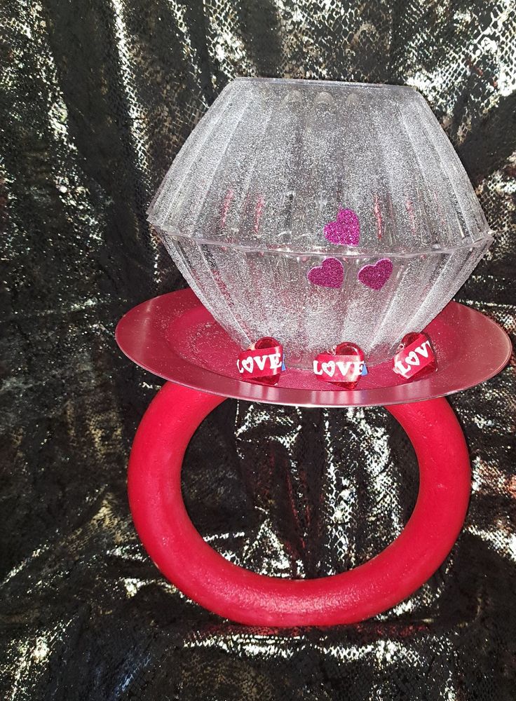 a plastic ring with candy in it sitting on top of a shiny cloth covered table