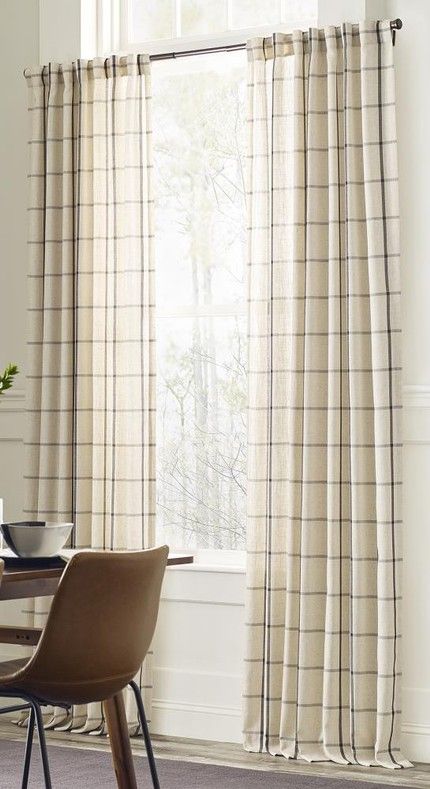 a dining room with a table and chairs next to a window covered in beige curtains