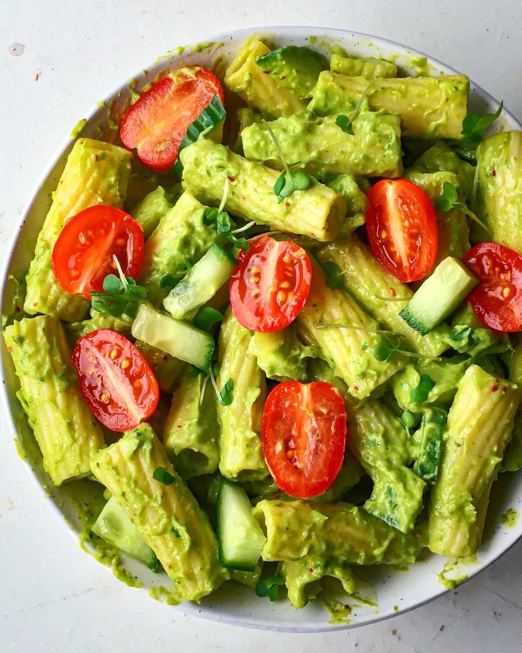 a bowl filled with avocado and tomatoes on top of a white countertop