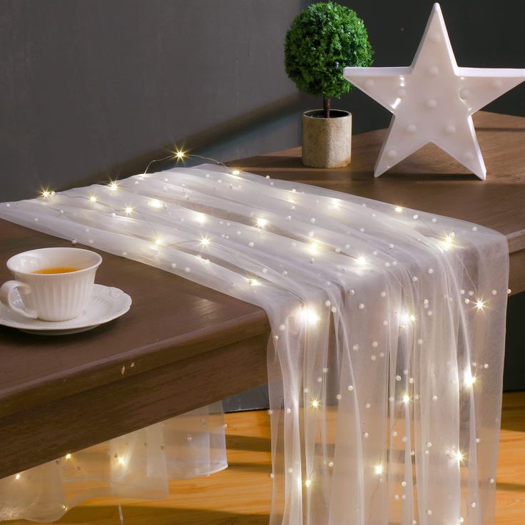 a table topped with a cup of coffee next to a star shaped light up decoration