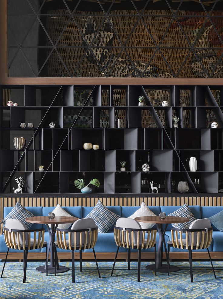 a room with several chairs and tables in front of a book shelf filled with books