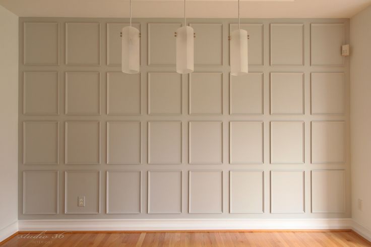 an empty room with white walls and wood flooring in the center is lit by three pendant lights that are hanging from the ceiling