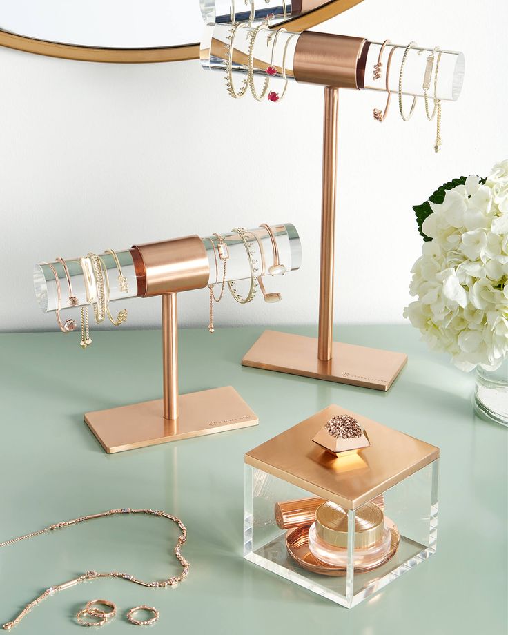 three pieces of jewelry sitting on top of a table next to a vase with flowers