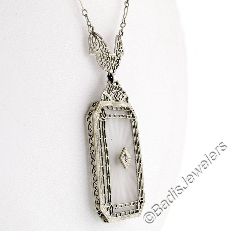 This is a gorgeous and VERY WELL MADE pendant necklace crafted during the art deco period in solid 14k white gold. It features a large, rectangular-shaped, camphor glass panel with cut corners and a stunning diamond set at its center. The pendant displays magnificent etching designs and open filigree work throughout its frame as well as the part that connects to the chain. The filigree work gives this piece its unique look and makes a special statement on this pendant. The lovely diamond is set Art Deco Diamond Necklace With Filigree Details, Art Deco Diamond Necklace With Filigree, Art Deco Diamond Cut Necklace For Anniversary, Victorian White Gold Necklace For Anniversary, White Gold Victorian Necklace For Anniversary, Victorian Style White Gold Necklace For Anniversary, Art Deco Platinum Necklace With Diamond Cut, Antique Rectangular Formal Necklace, Victorian White Gold Diamond Necklace For Anniversary