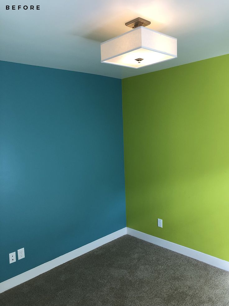 an empty room with blue and green walls, carpeted flooring and a square light fixture on the ceiling