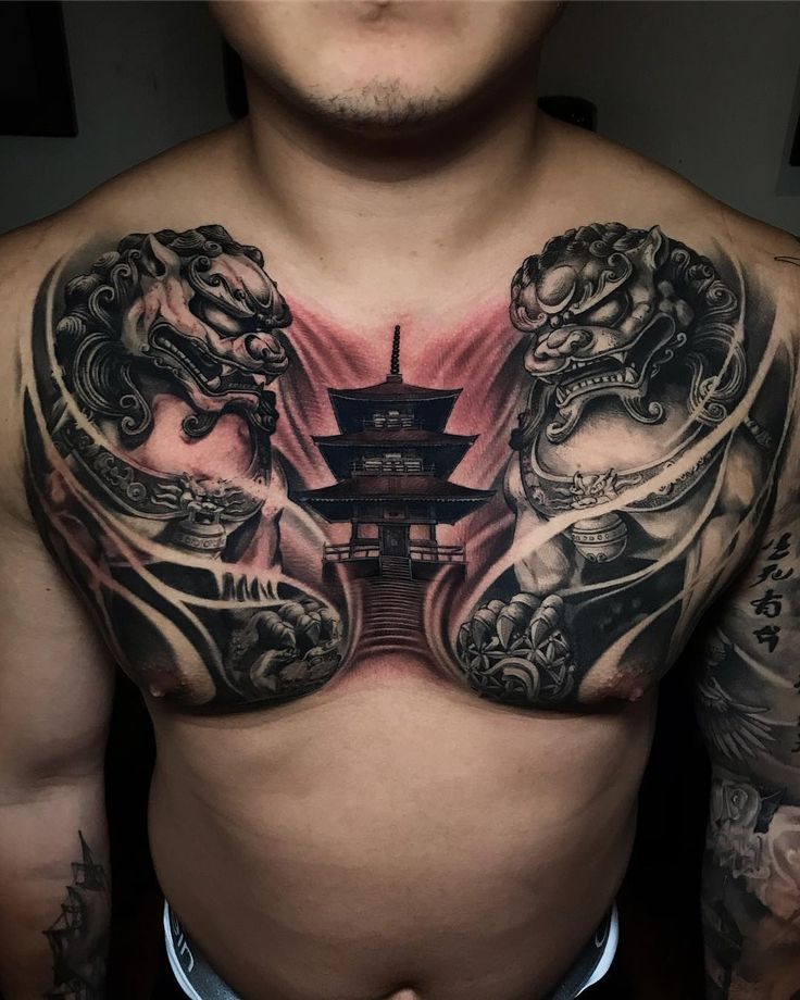 a man with tattoos on his chest is standing in front of a building and two dragon