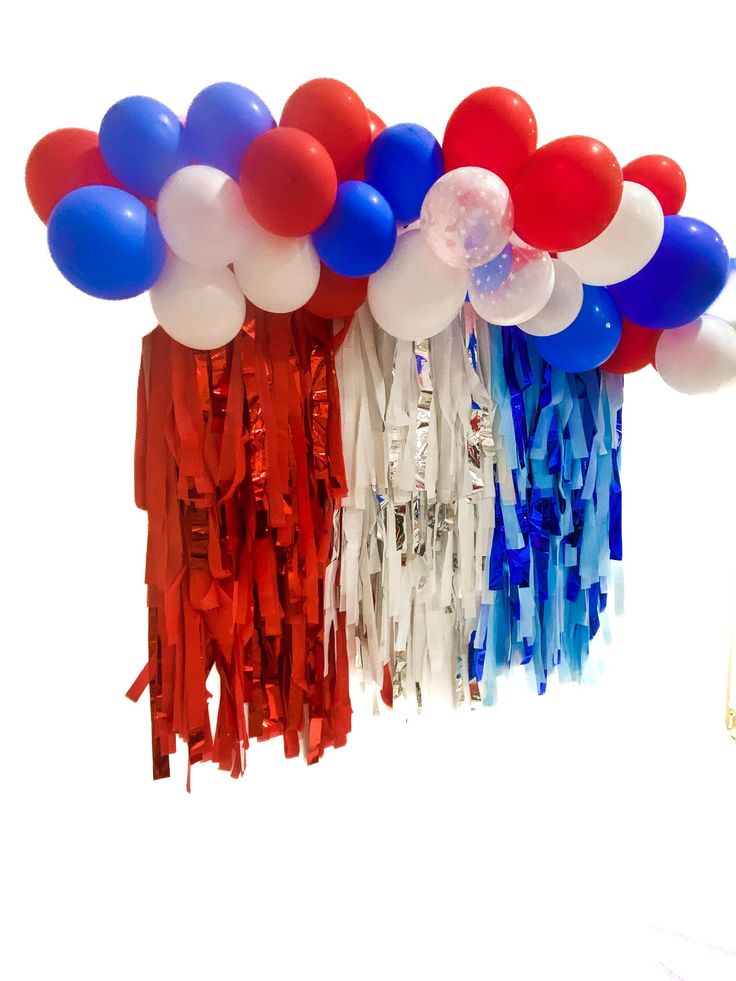 red, white and blue balloons are hanging from the ceiling