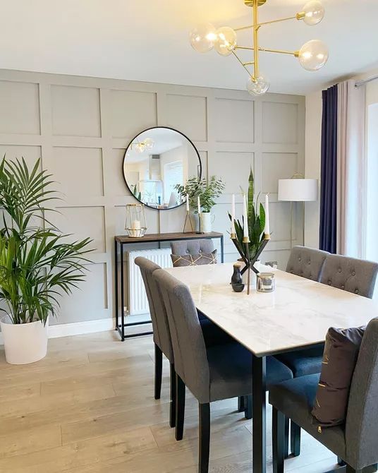 a dining room table with chairs and a mirror on the wall in front of it