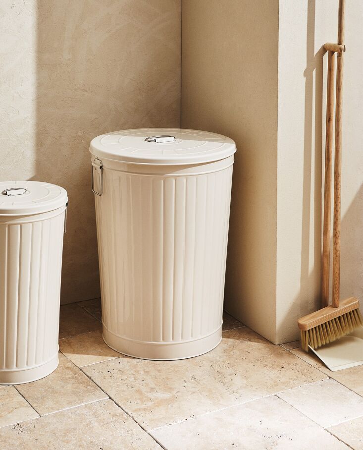 two trash cans sitting next to each other on the floor in front of a wall