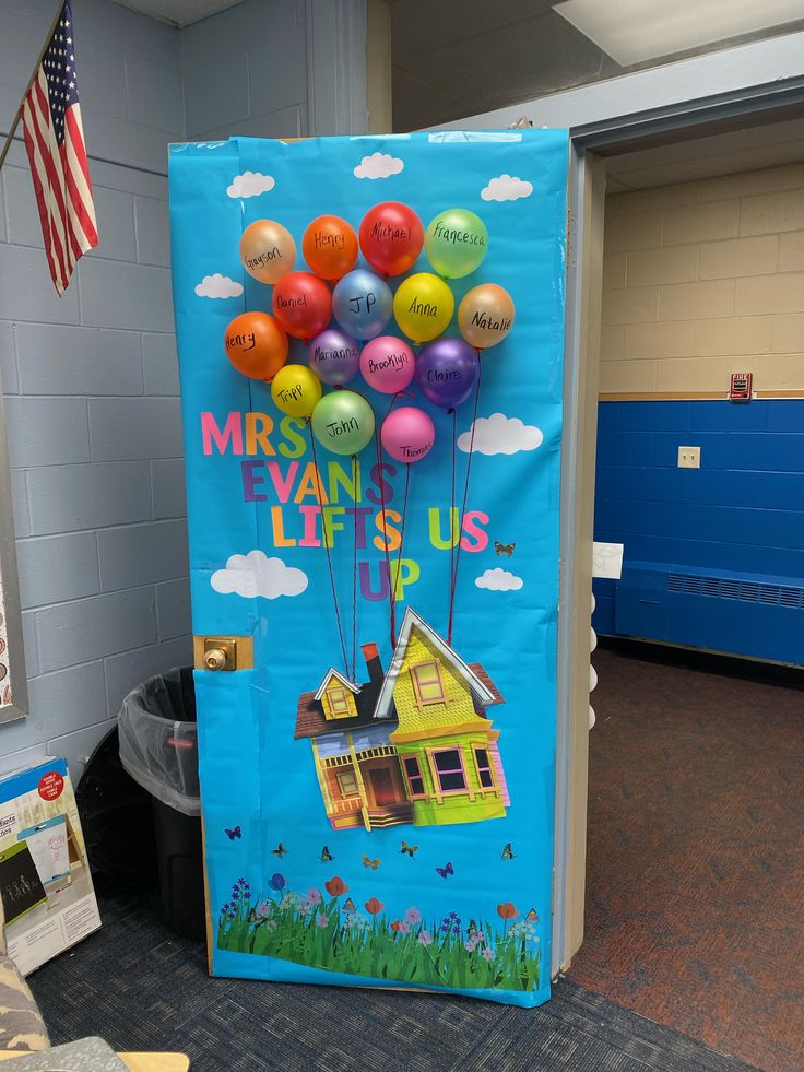 a bulletin board with balloons attached to it in a school hallway, next to a trash can