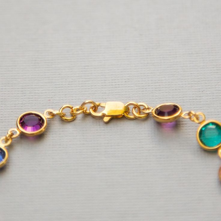 "Dainty, custom Mother's bracelet in gold with Swarovski Crystal birthstones. This sparkling birthstone bracelet would make a perfect gift for a mother or grandmother, with Swarovski crystals, set in gold, representing the birthstones of their family members. I can make this bracelet in a variety of ways for you. The photos above show some of the options: * a row of birthstones surrounded on either side by clear crystals * a repeated pattern of colors * a single color <>How to Order<&gt Gold Gemstone Bracelets As Gift, Gold Gemstone Bracelet For Birthday, Gold Charm Bracelet With Birthstone For Anniversary, Gold Bracelet For May Birthstone Gift, Gold Oval Bracelet With Bezel Setting, Oval Gold Bracelet With Bezel Setting, Gold Bracelets For Anniversary With May Birthstone, Gold Round Bracelet With Birthstone, Adjustable Bracelets With Bezel Setting As Gift