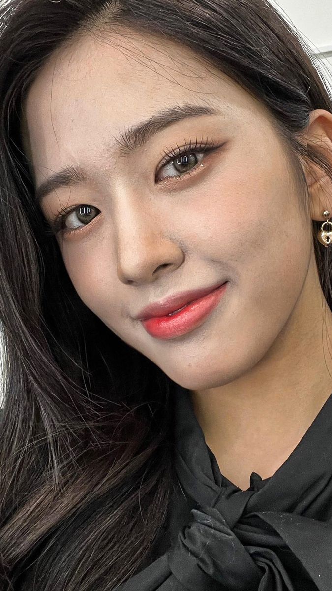 a woman with long dark hair wearing a black shirt and gold hoop earrings, posing for the camera