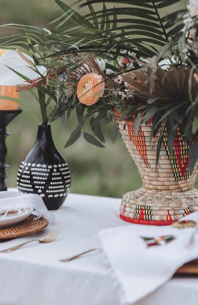 two vases with plants in them sitting on a table next to plates and napkins