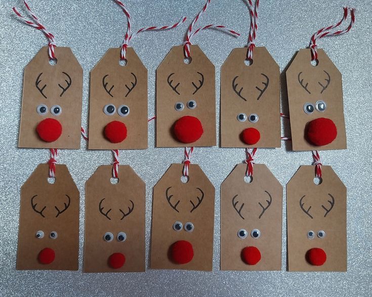 christmas gift tags with reindeer faces and noses are hanging from twine on a table