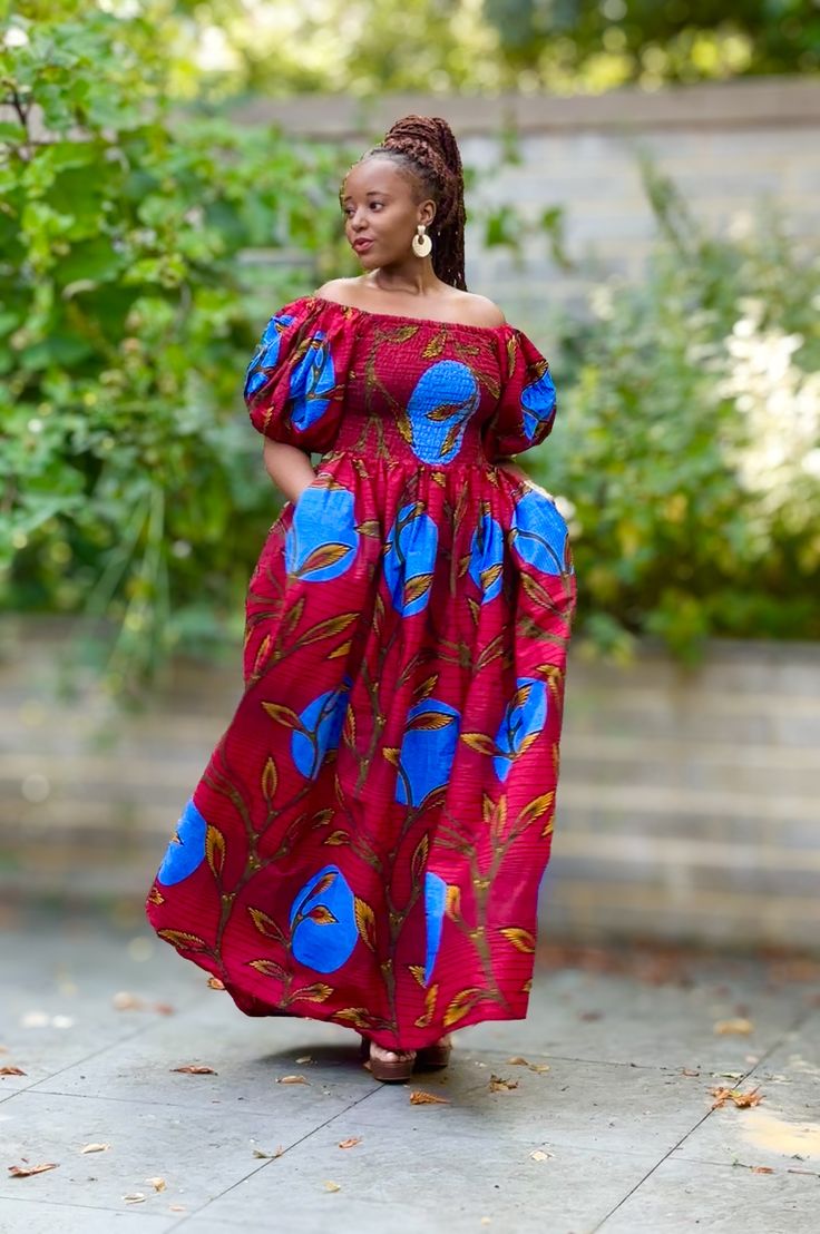 A beautiful statement dress with side pockets in a contemporary African print in a vibrant red with a bold floral pattern. It has smocking from the bust to the waist with a full skirt to the dress and adjustable exaggerated puff sleeves which can be worn off or on shoulder. An easy to wear pull on piece that may be styled for an informal outing or a formal occasion by selecting the appropriate accessories and footwear.100% Cotton. Handmade in Ghana. HAVE YOU CHECKED YOUR MEASUREMENTS AGANST THE Dress With Puff Sleeves, Maxi Skirt Dress, Statement Dress, African Dresses, African Design Dresses, Jumpsuit Trousers, African Design, African Dress, Full Skirt