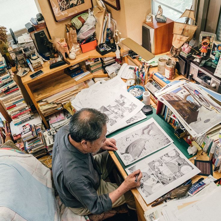 a man sitting at a desk working on some drawings