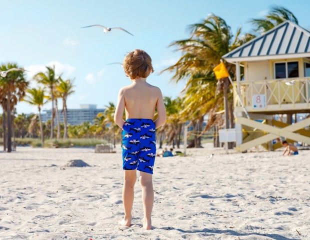 a young boy standing on top of a sandy beach