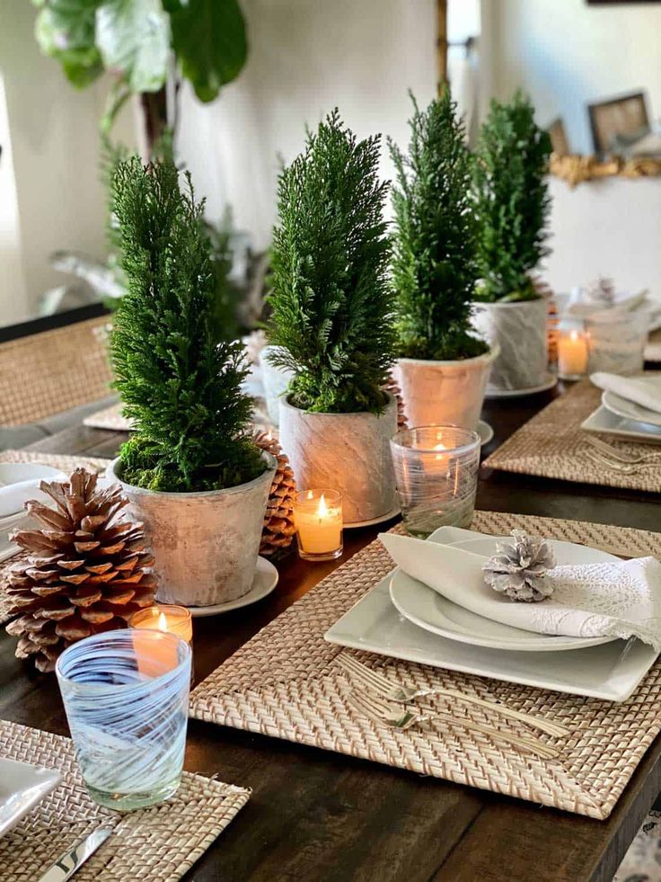 the table is set with pine cones and place settings