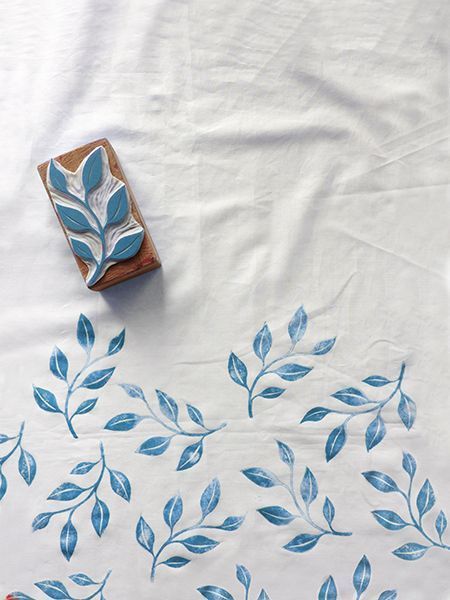 a white table cloth with blue leaves on it, next to a rubber stamp and a wooden block