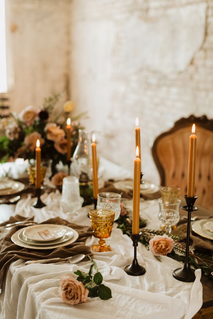 the table is set with candles, plates and napkins for an elegant dinner party