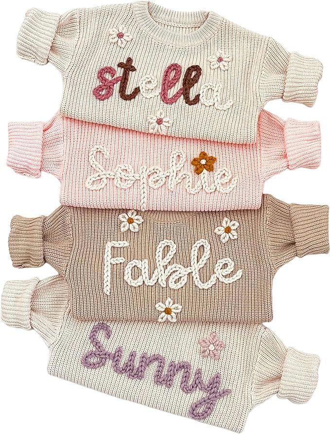 three sweaters with words on them are shown in different colors and sizes, one is pink