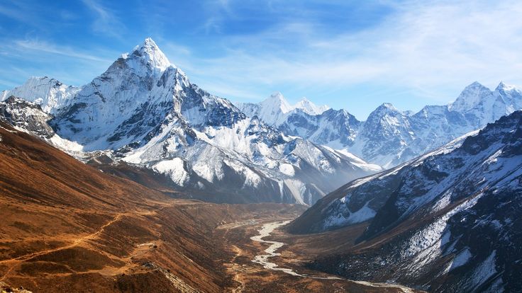 the mountains are covered in snow and brown grass