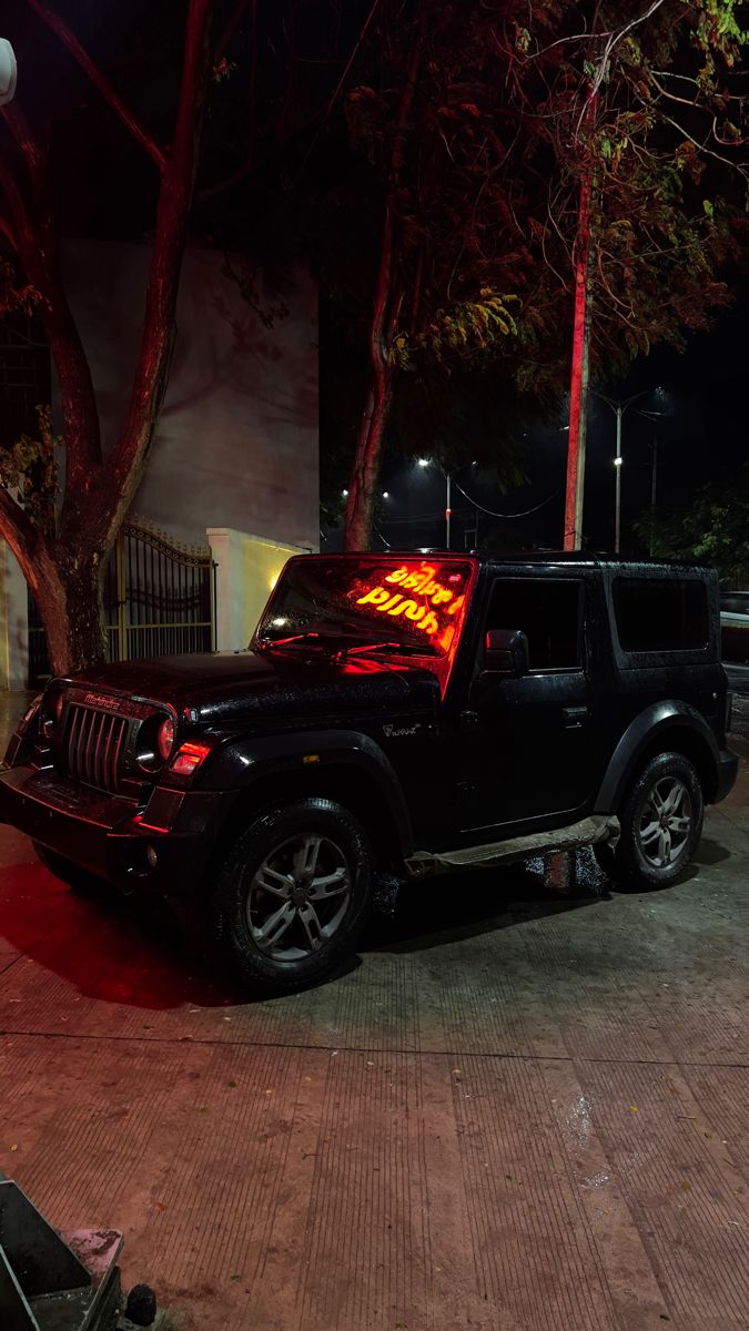 a black jeep parked next to a tree at night