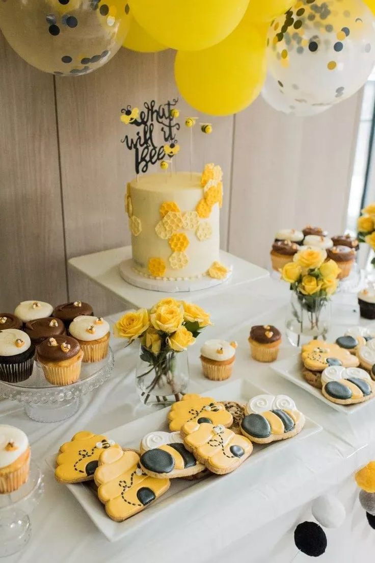 a table topped with lots of yellow cupcakes and cakes covered in frosting