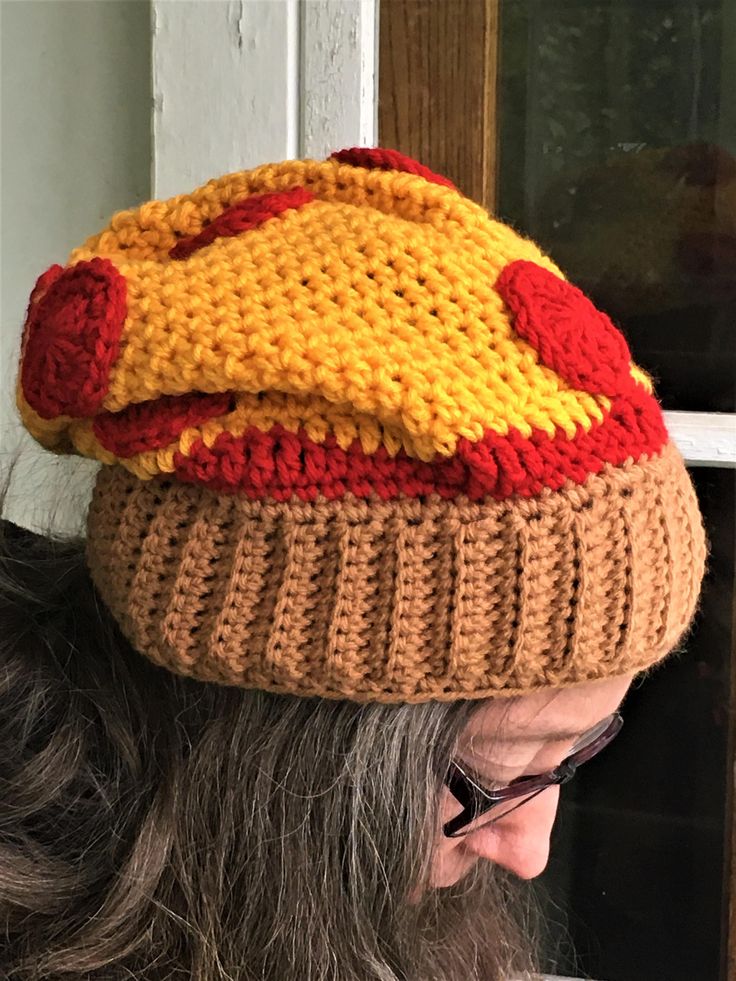 a woman wearing a knitted hat with red, yellow and orange designs on it