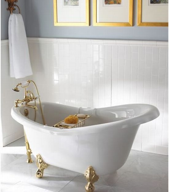 a white bath tub sitting in a bathroom next to two framed pictures