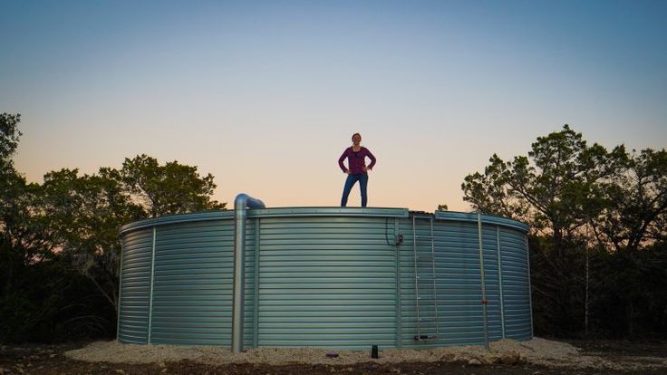 a man standing on top of a metal tank